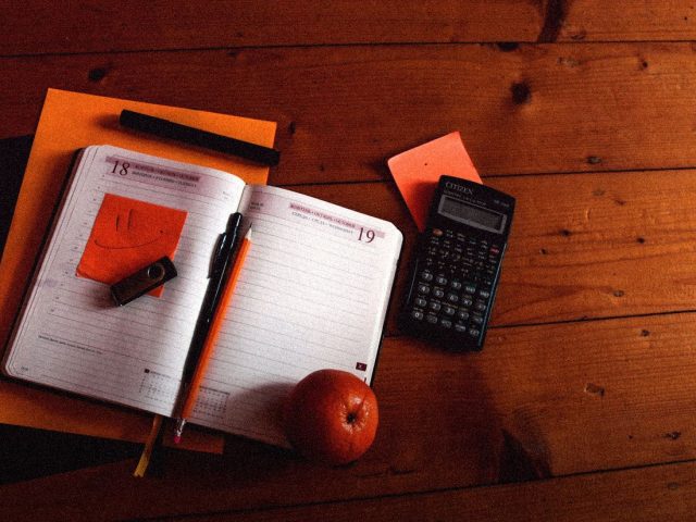 Notebook, pen and calculator on a wooden desk, best budgeting apps in the US