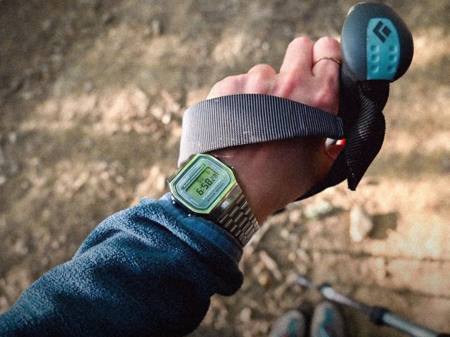 GPS watch on a hiker's wrist with a trekking pole, best GPS watches for hiking