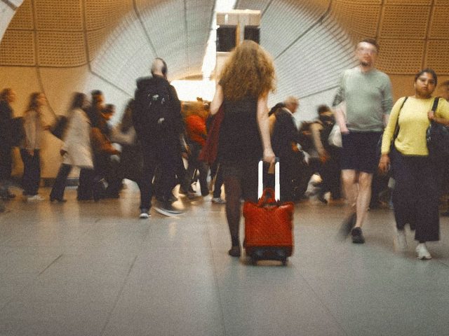 Traveller pulling a red suitcase through an airport, best travel insurance UK