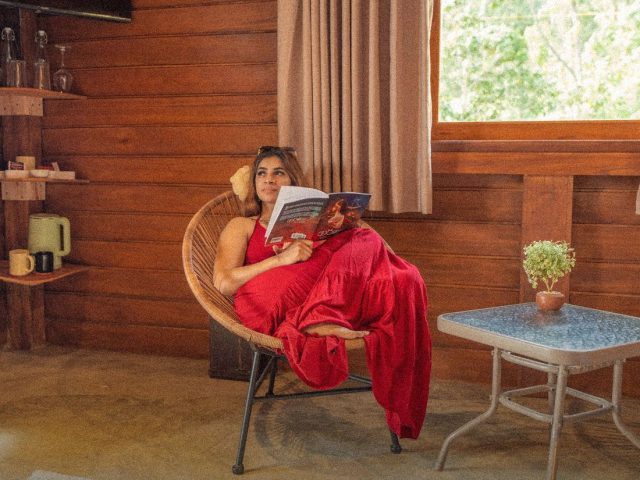 Woman reading a magazine in a wicker chair, best travel magazines