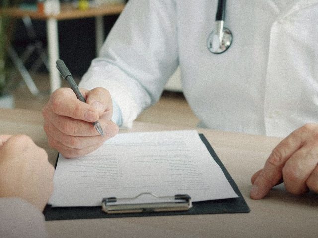 Doctor writing on a clipboard during a consultation, Clinique La Prairie Revitalisation