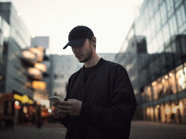 Young man checking his phone in the city, Current banking app review