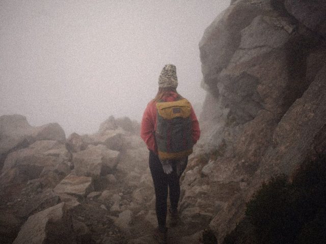 Hiker on a rocky path in mountain fog, hiking exoskeletons