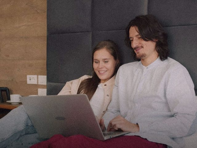 Couple booking a hotel on a laptop, hotel booking discount codes