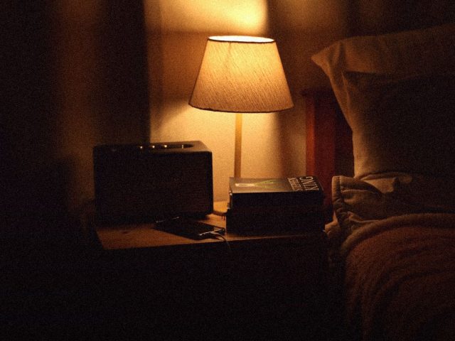 Bedside lamp glowing beside a bed at night, sleep tracker accuracy