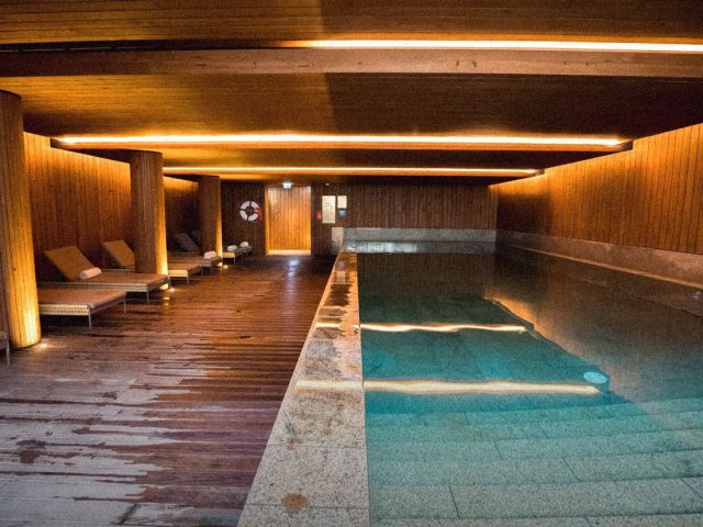 Candlelit indoor spa pool with wooden deck, luxury hotels with longevity clinics