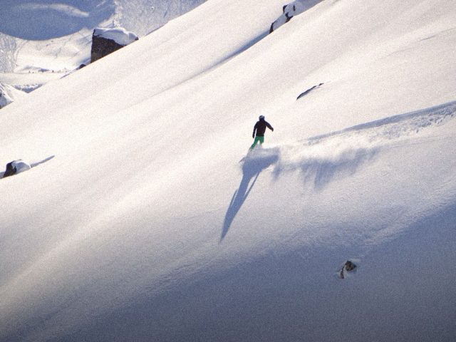 Skier carving fresh tracks on an open snow slope, off-piste ski insurance
