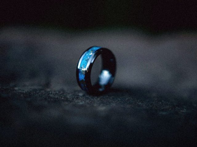 Smart ring lit in blue on a dark surface, Oura Ring review