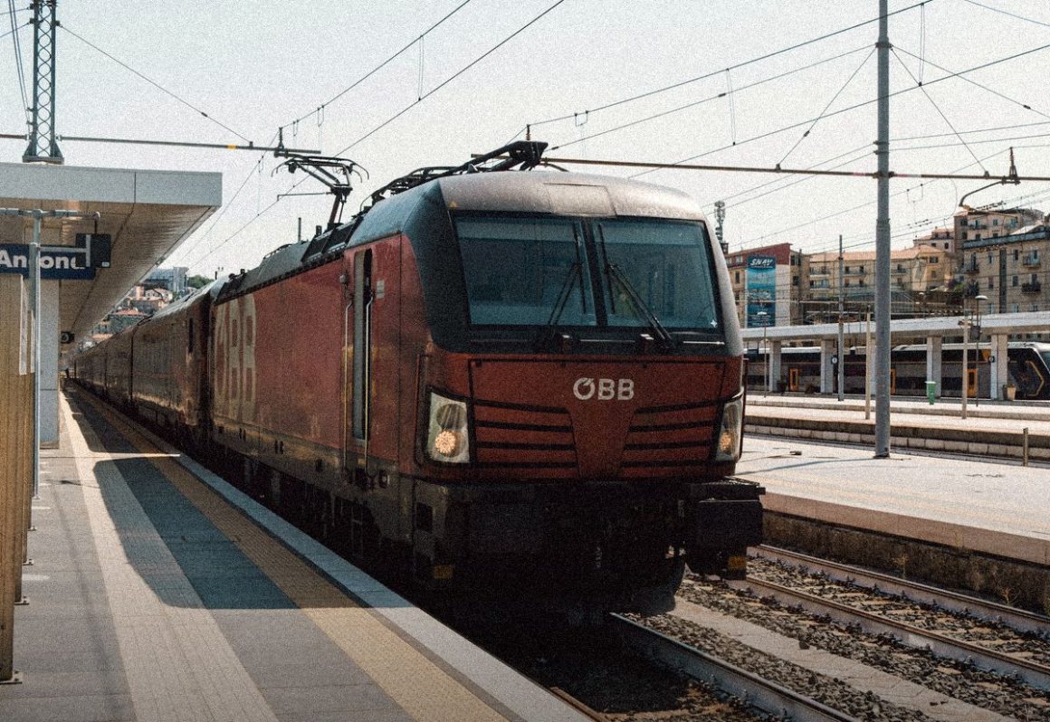 Red electric locomotive at a European station, travel insurance for EU residents