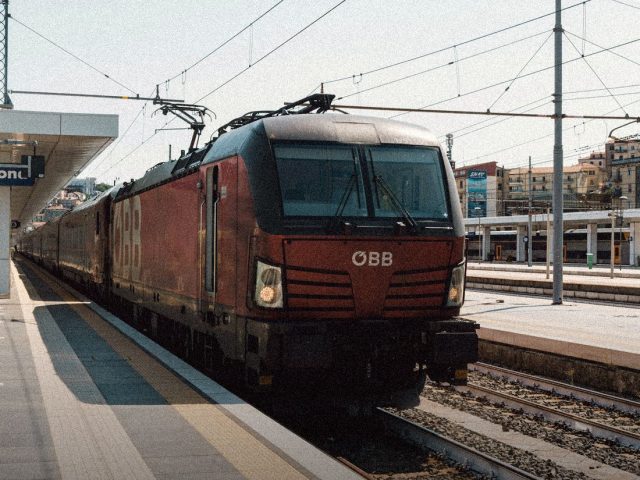 Red electric locomotive at a European station, travel insurance for EU residents