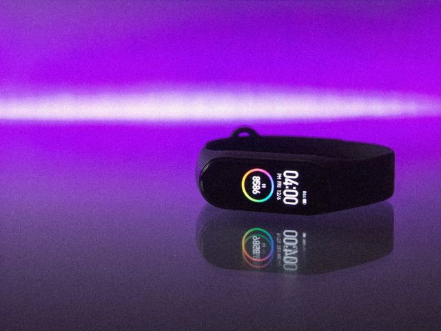 Fitness band on a reflective surface under violet light, WHOOP vs Oura vs Garmin