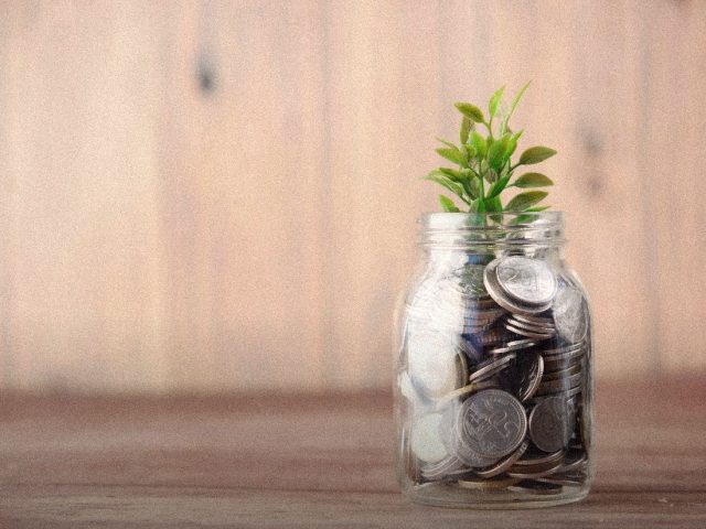 Glass jar of coins with a small plant, YNAB budgeting app review