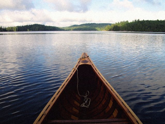 Bow of a canoe on a calm wilderness lake, ZOLEO satellite messenger review