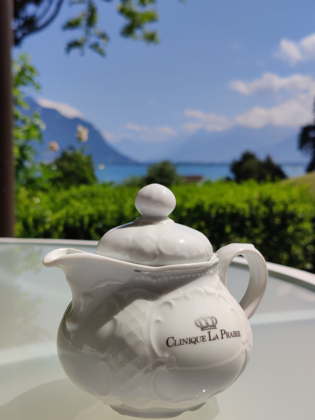 Clinique La Prairie branded teapot on a terrace table with Lake Geneva and the Alps behind